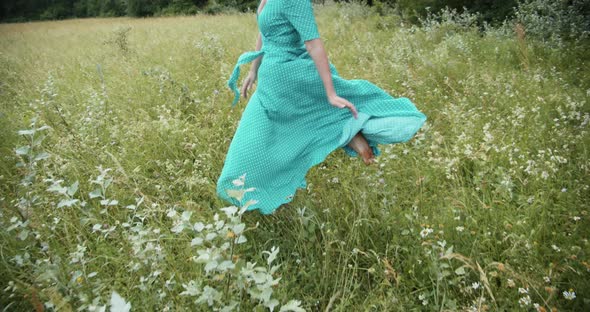 A Girl In A Long Dress Runs Across A Green Meadow