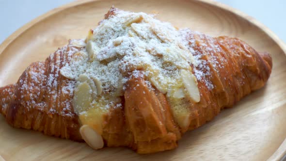 The croissants with almond and milk on the wooden plate are spinning.