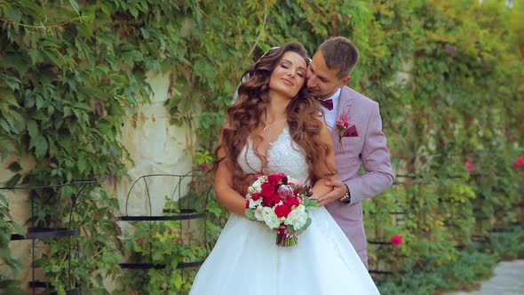 the Groom Gives the Bouquet To the Bride and They Kiss Near Modern Castle Slow Motion Handy Camera