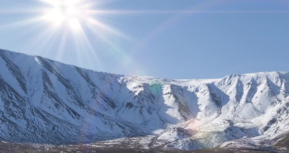 Timelapse of Sun Movement on Crystal Clear Sky Over Snow Mountain Top. Yellow Grass at Autumn Meadow