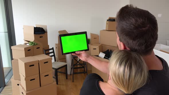 A Moving Couple Looks at a Tablet with Green Screen in an Empty Apartment