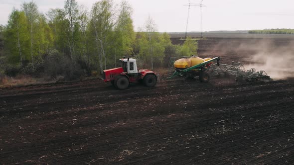 Aerial View of at Agriculture Tractor Sowing Seeds and Cultivating Field in Late Afternoon