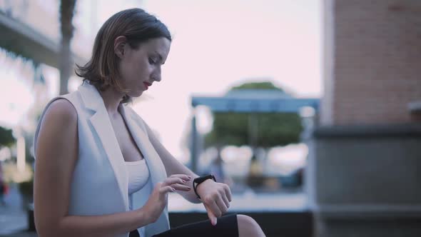 Young Elegant Businesswoman Using Smartwatch During Break in City