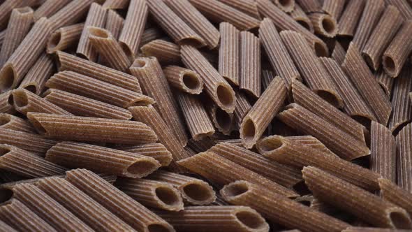 Dry buckwheat italian pasta penne closeup. Uncooked whole macaroni