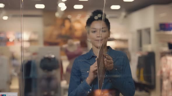 Young African American Woman Turning a Sign From Closed to Open on the Door of a Women's Brand