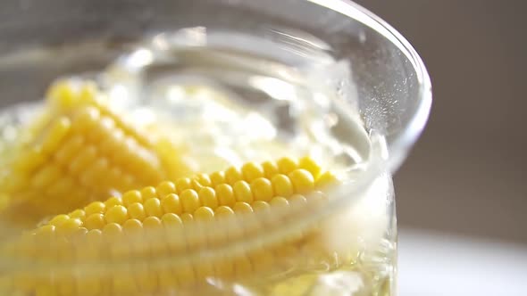 Ripe Corn Cobs In Boiling Water. Organic Yellow Corn In Glass Saucepan With Boiling Water. Cooking