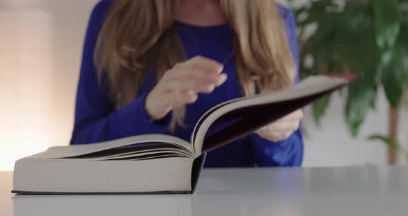 A woman opens a book.