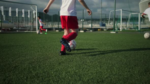 Boy in Football Uniform with Untied Laces Dribbles Ball