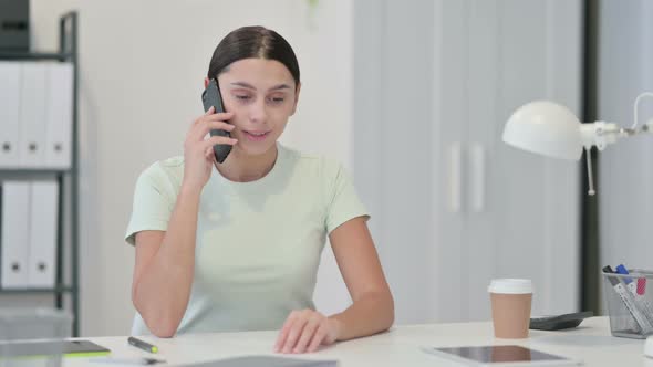 Young Latin Woman Talking on Phone at Work