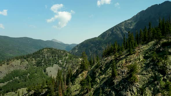 Flying over the Colorado Rocky Mountains to reveal a highway in the valley below