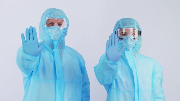 Doctor and Nurse, in Special Protective Suits, Uniforms, Masks, Goggles, Looking at Camera, Showing