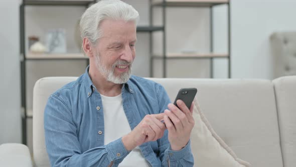 Old Man Using Smartphone While Sitting on Sofa