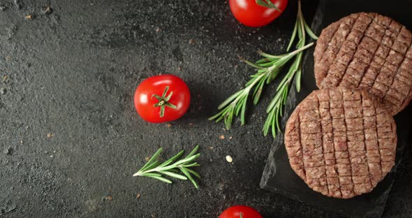 Raw Burger Meat on Stone Board with Tomatoes and Rosemary. 