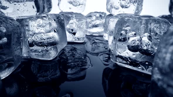 Camera Moving Away From Melting Ice Cubes with Bubbles. Abstract Close-up Shot