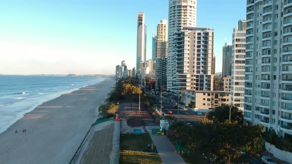 Aerial view of high-rise buildings casting a shadow on a popular tourist beach