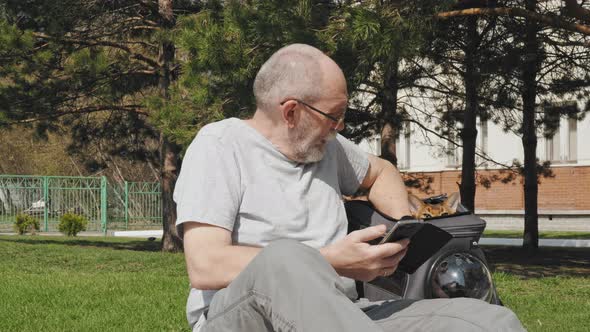 Man sits near a backpack with a cat inside