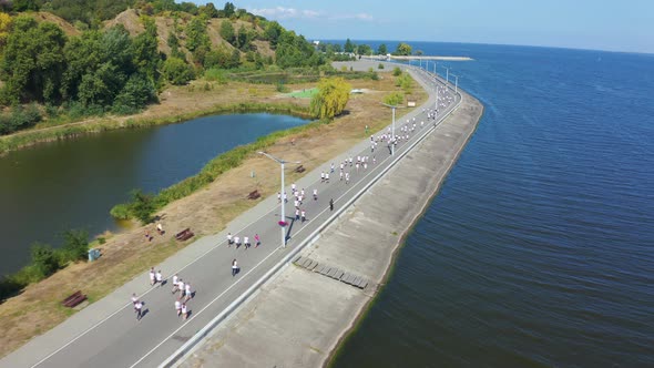 Marathon Runners in White T-shirts Running Along the Promenade. Aerial View Footage