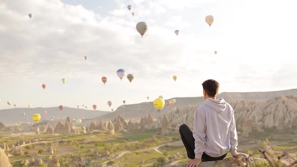 Young Man Sits And Looking To The Air Balloons.