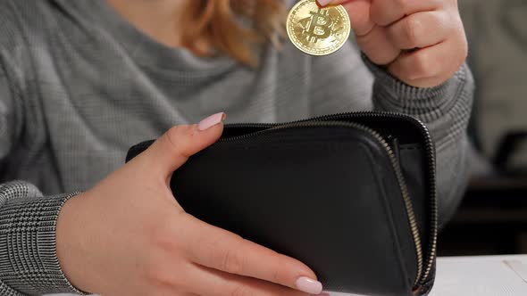 Closeup of a Woman Putting a Bitcoin Coin Into a Wallet