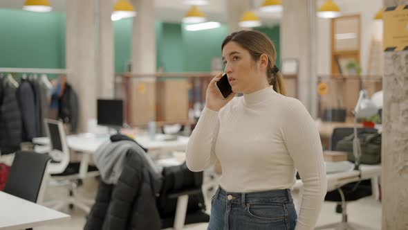 Office Worker Standing in Coworking Space and Talking on the Phone with Worried Facial Expression