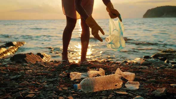 Volunteer Girl Collects Trash in the Trash Bag. Plastic Bottles and Other Trash on Sea Beach