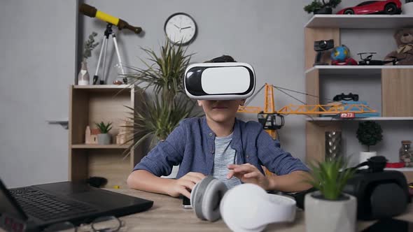  Teen Boy Looking at Camera and Wearing Virtual Reality Headset to Play Video Games