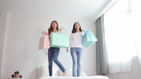 Young Asian woman packing clothes to the suitcase sitting on the bed.