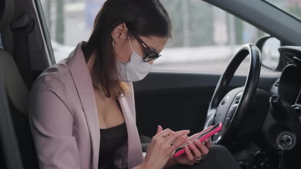 Female Driver Inside Car is Sending Message By Smartphone Woman is Wearing Mask