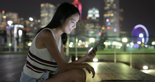 Woman looking at mobile phone in the city at night 