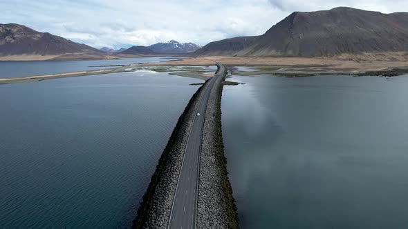 Car driving over long Sword shaped bridge causeway through ocean bay in Iceland