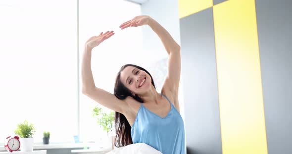 Smiling Woman Pulls Her Hands Up While Sitting in Bed