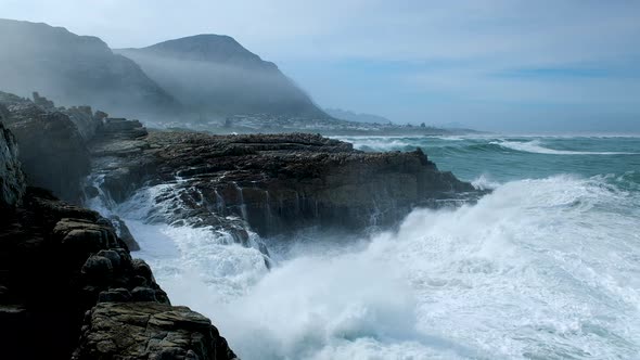 Huge wave making a big splash as it crashes into rocks on rocky coastline, Hermanus