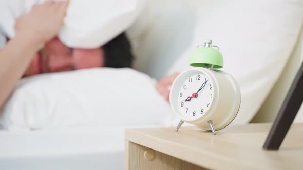 Asian attractive young man turn off alarm clock ringing in the morning.