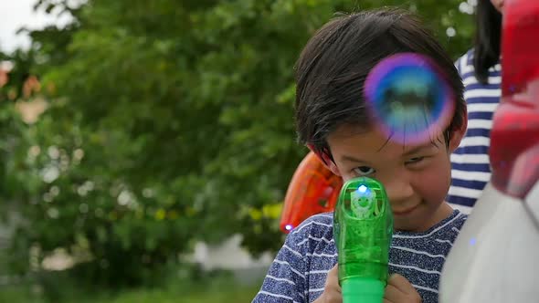 Cute Asian Child Shooting Bubbles From Bubble Gun