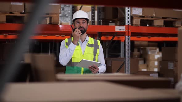 Engineer Communicating By Radio Set in Warehouse