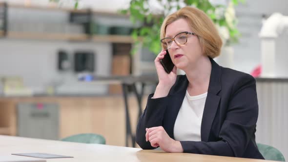 Cheerful Businesswoman Talking on Smartphone in Office