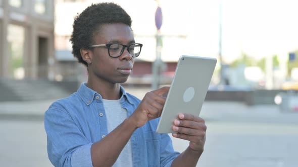 Young African Man Celebrating Online Win on Tablet Outdoor