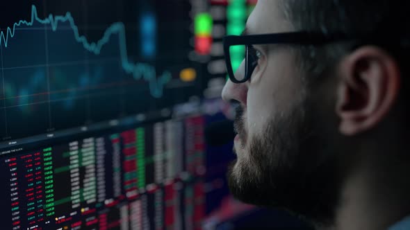 Trader is Working with Multiple Computer Screens Full of Charts and Data Analysis and Stock Broker
