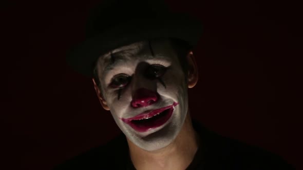 Scary Man in a Clown Makeup Looks at the Camera and Laughs