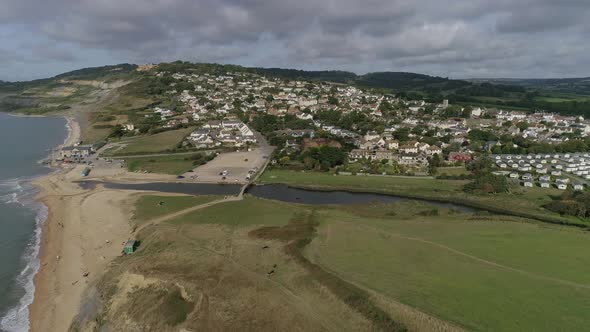 Aerial of the village of Charmouth from the east. Tracking forward to the village further inland and