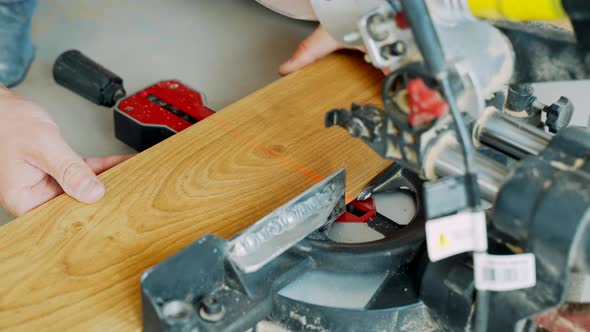 A Worker Cuts Off a Laminated Board with an Electric Miter Saw. Laying the Floor Covering.