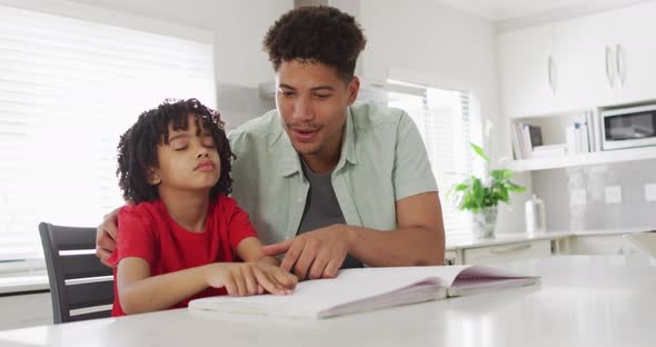 Happy biracial man and his son reading braille together