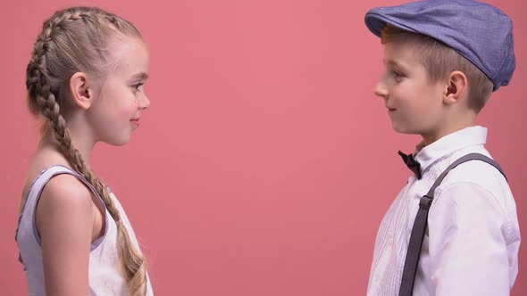 Cheerful Kids Couple Cuddling and Looking to Camera, Isolated on Pink Background