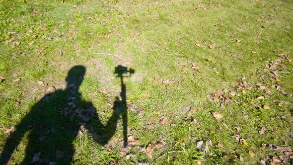 Operator Shadow Moves in Hurry Filming Grass with Camera