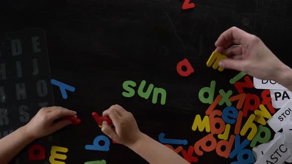 Mom teaches her son how to say the words on the cards and letters