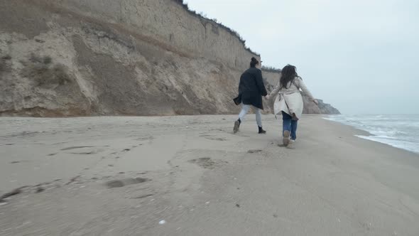 Happy Couple Run on the Wild Beach on Cloudy Sunrise