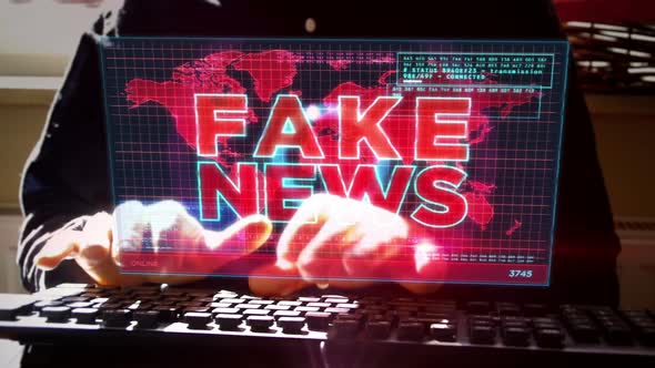 Man typing on keyboard with Fake news on hologram screen