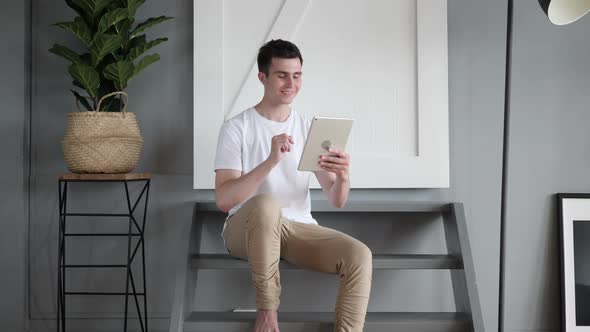 Online Video Chat on Tablet By Man Sitting on Stairs