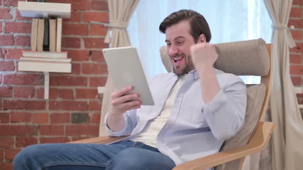 Casual Young Man Celebrating Success on Tablet on Sofa