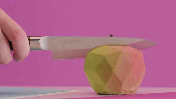 Pastry Chef Cuts Branded Dessert in the Form of an Apple on Colored Pink Background